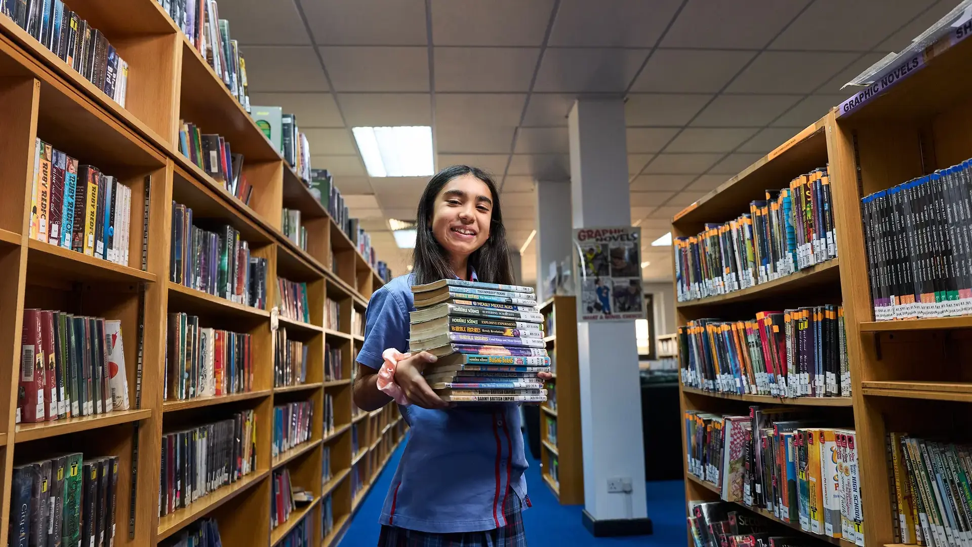 Student holding books in library